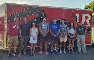 scholarship winners and club members standing in a row in front of the utica roadrunners trailer